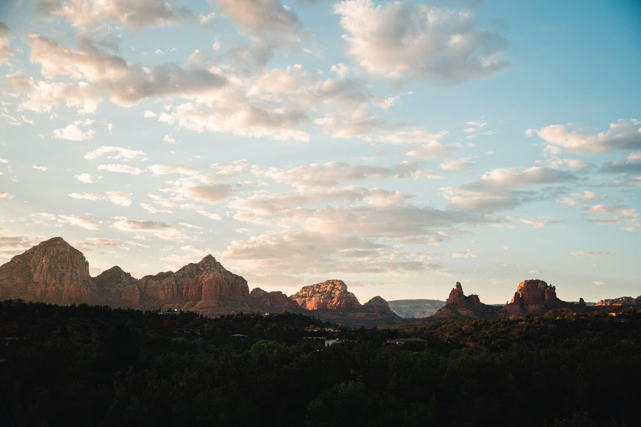Sedona red rocks glowing at sunset under layered clouds.